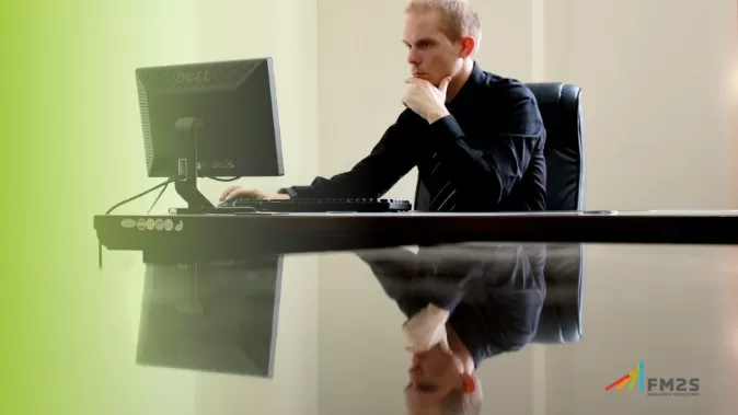 À esquerda degradê verde. Ao fundo, homem utilizando computador. No canto inferior direito, o logotipo da FM2S,